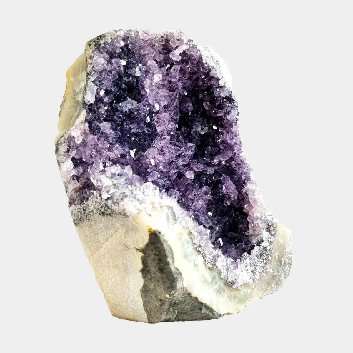Side angle view of a small amethyst geode showing dark violet crystals, white quartz, and the cut natural stone side.