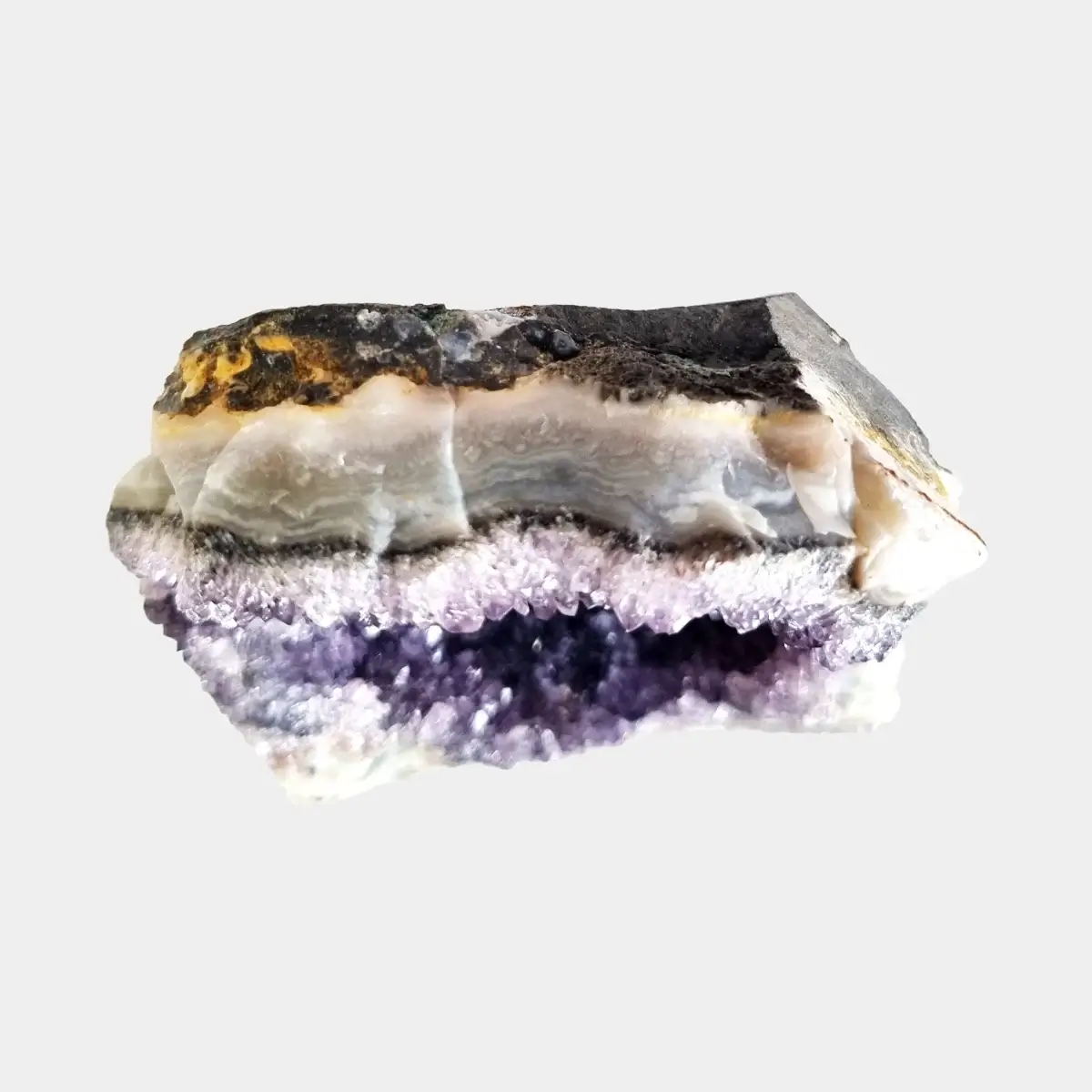 Top view of a small amethyst geode showing layered stone, pale quartz, and a narrow line of purple crystals.